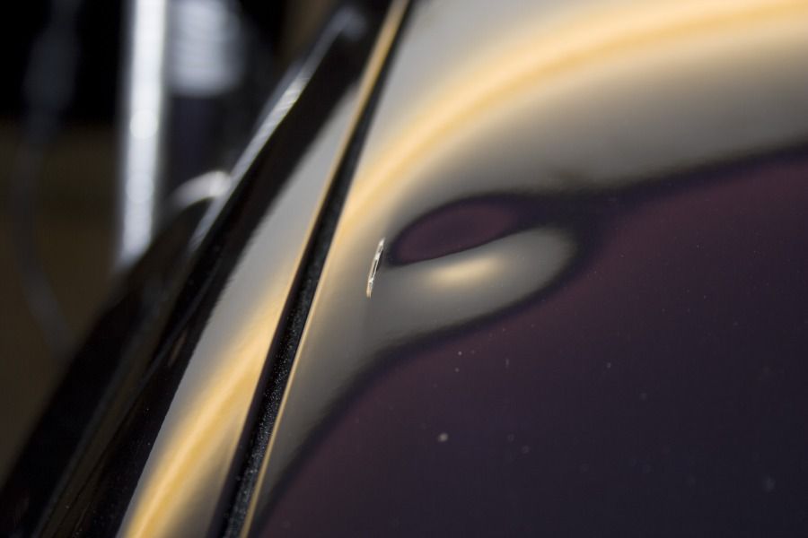 Close-up of a small door ding catching the light
